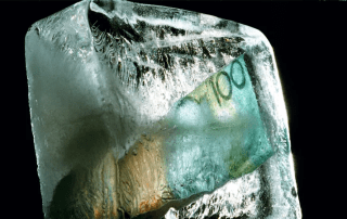 investment funds frozen - depicted by an Australian $100 note frozen in a block of ice