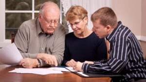 family taking financial planner guidance in the wealth mnanagement preparation of their next generation sitting in living room reading documents