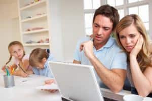 Young Couple reviewing family budget under watchful eye of children