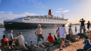 peoplke at harbour edge longingly watching a cruise ship departing port