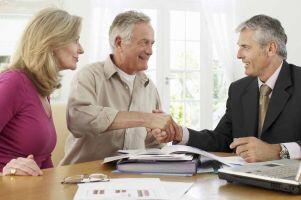 mature-ages couple with adviser and the men shaking hands agreeing on ongoing adviser service