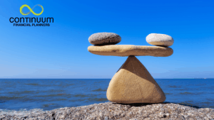stones balanced on a rock fulcrum with a clear blue sky and a calm blue sea background