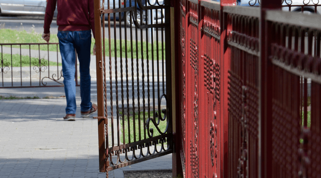 man walking along fence precluded from access to greener field