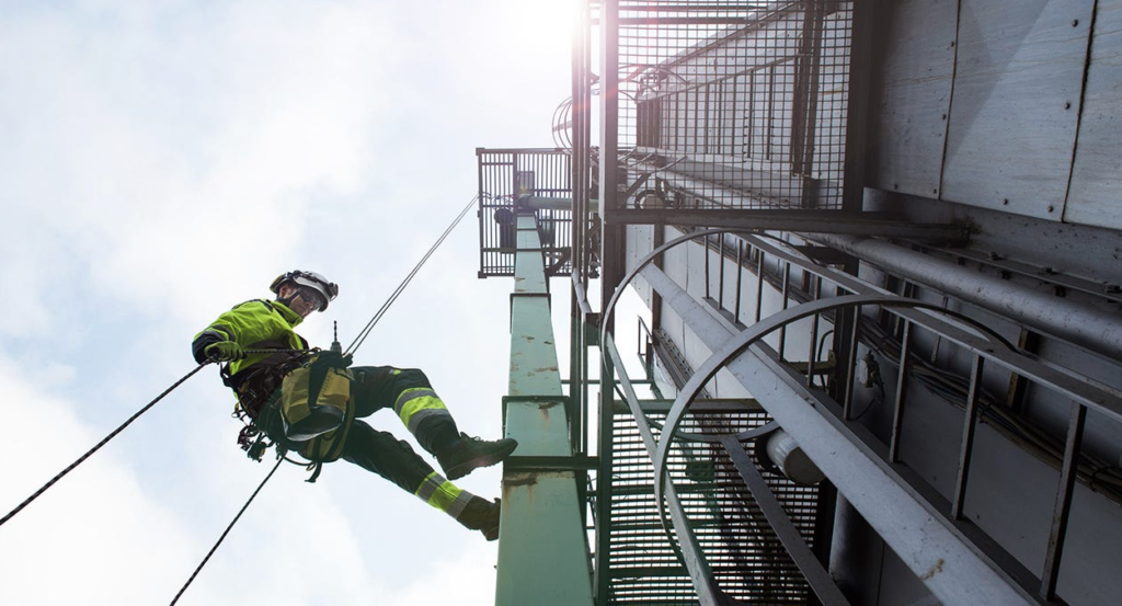 worker in high visibility safety clothing abseiling down tower